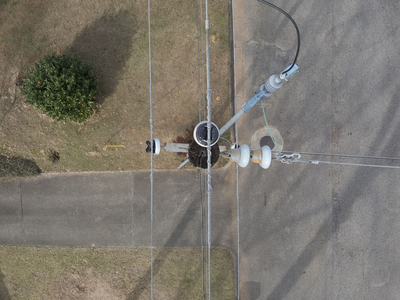Top-down drone photo of a distribution pole beside a road.